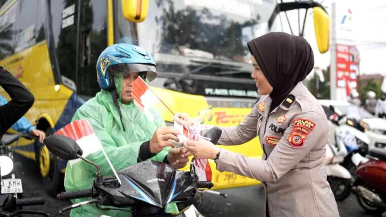 Anggota Polres Bogor membagikan bendera merah putih di Jalan Raya Tegar Beriman, Cibinong, Kabupaten Bogor, Jawa Barat, Rabu (6/8/2025).